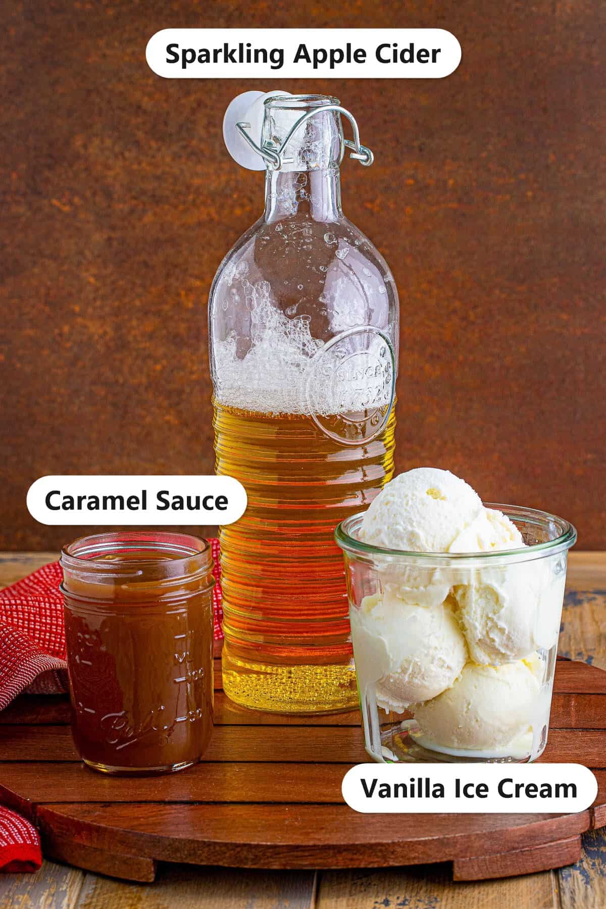 Labeled ingredients for an apple cider float including sparkling apple cider, vanilla ice cream, and caramel sauce.