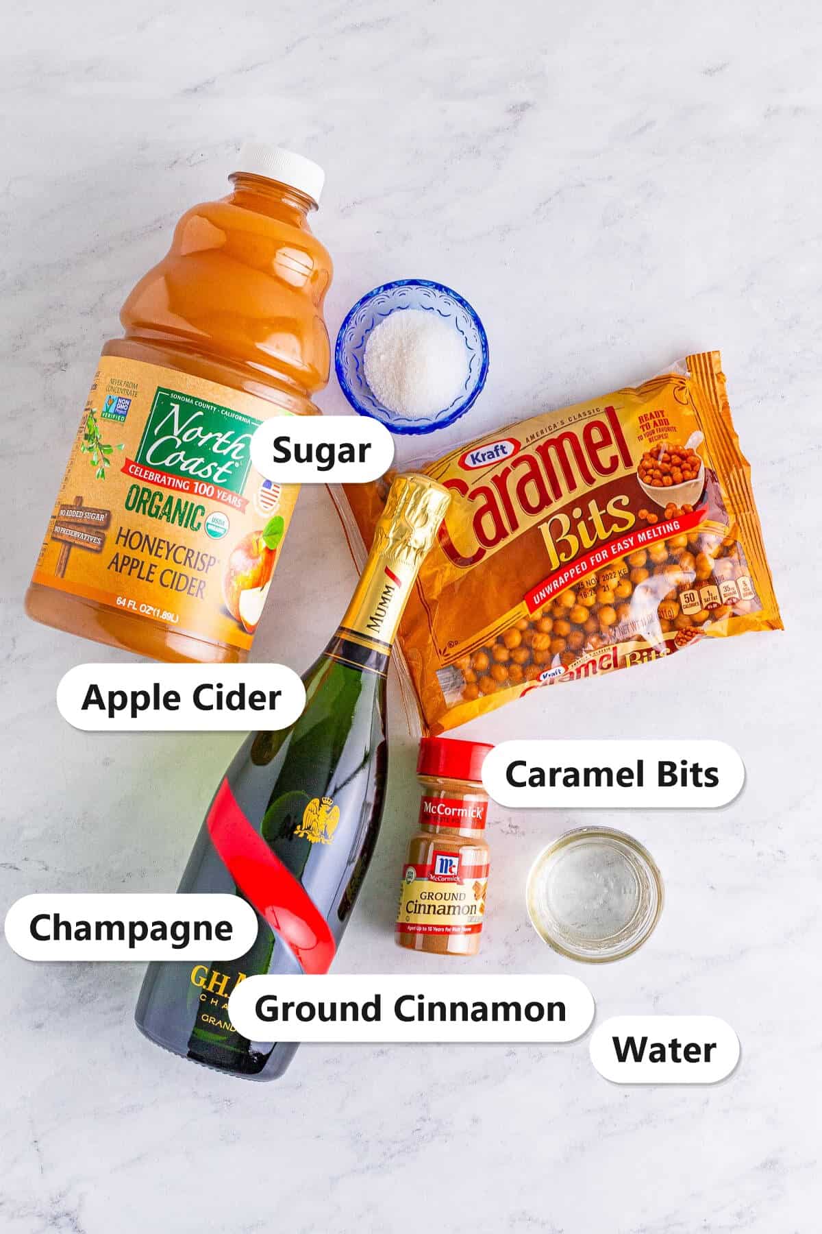 Ingredients to make apple cider mimosas: apple cider, champagne, caramel bits, sugar, ground cinnamon, and water.