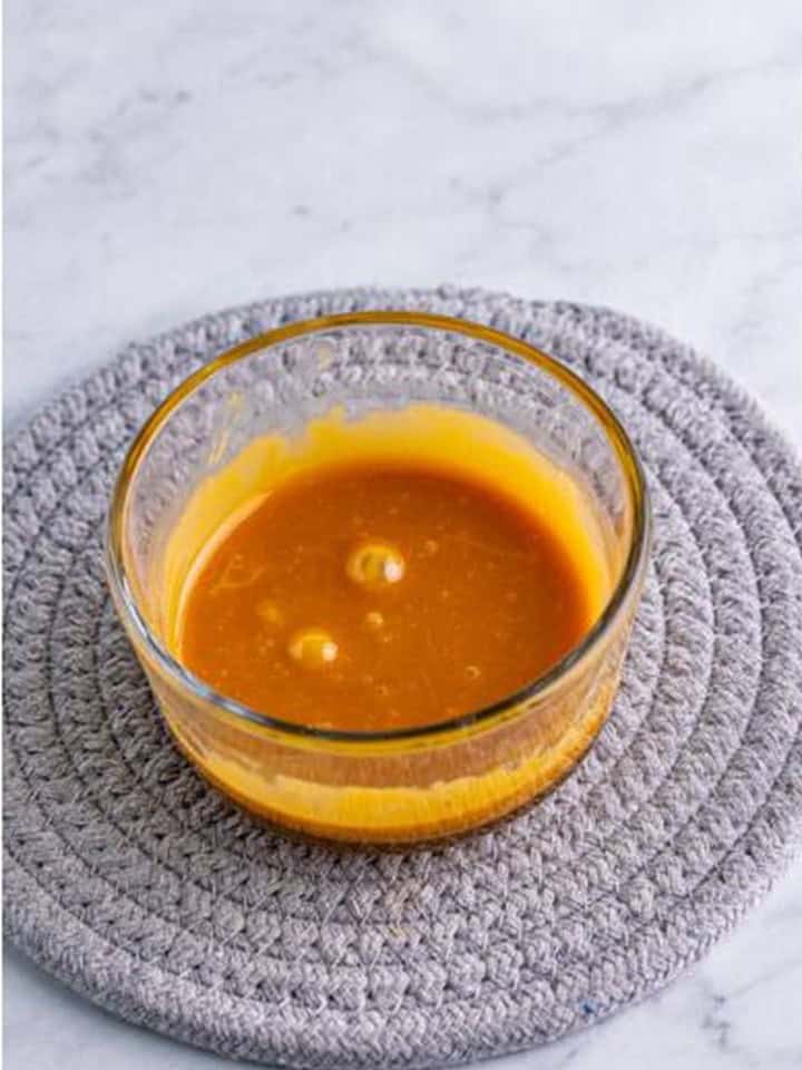 Melted caramel bits in a small glass bowl for rimming mimosa glasses.