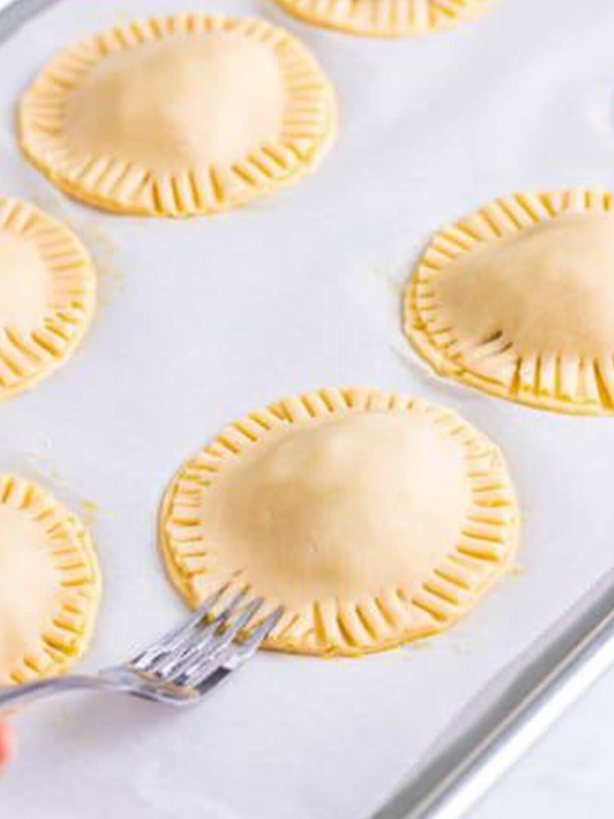 Sealing the edges of each apple hand pie together with a fork.