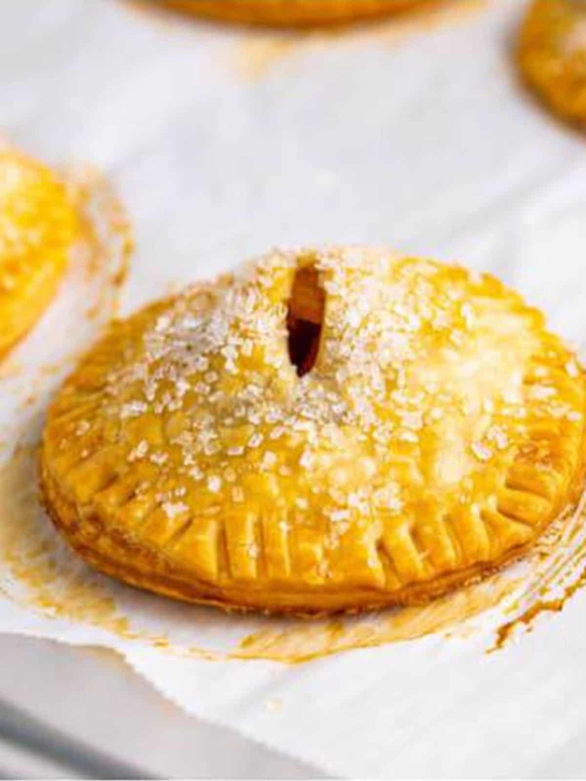 A baked golden Apple Hand Pie with a vent slit and sparkling sugar top.