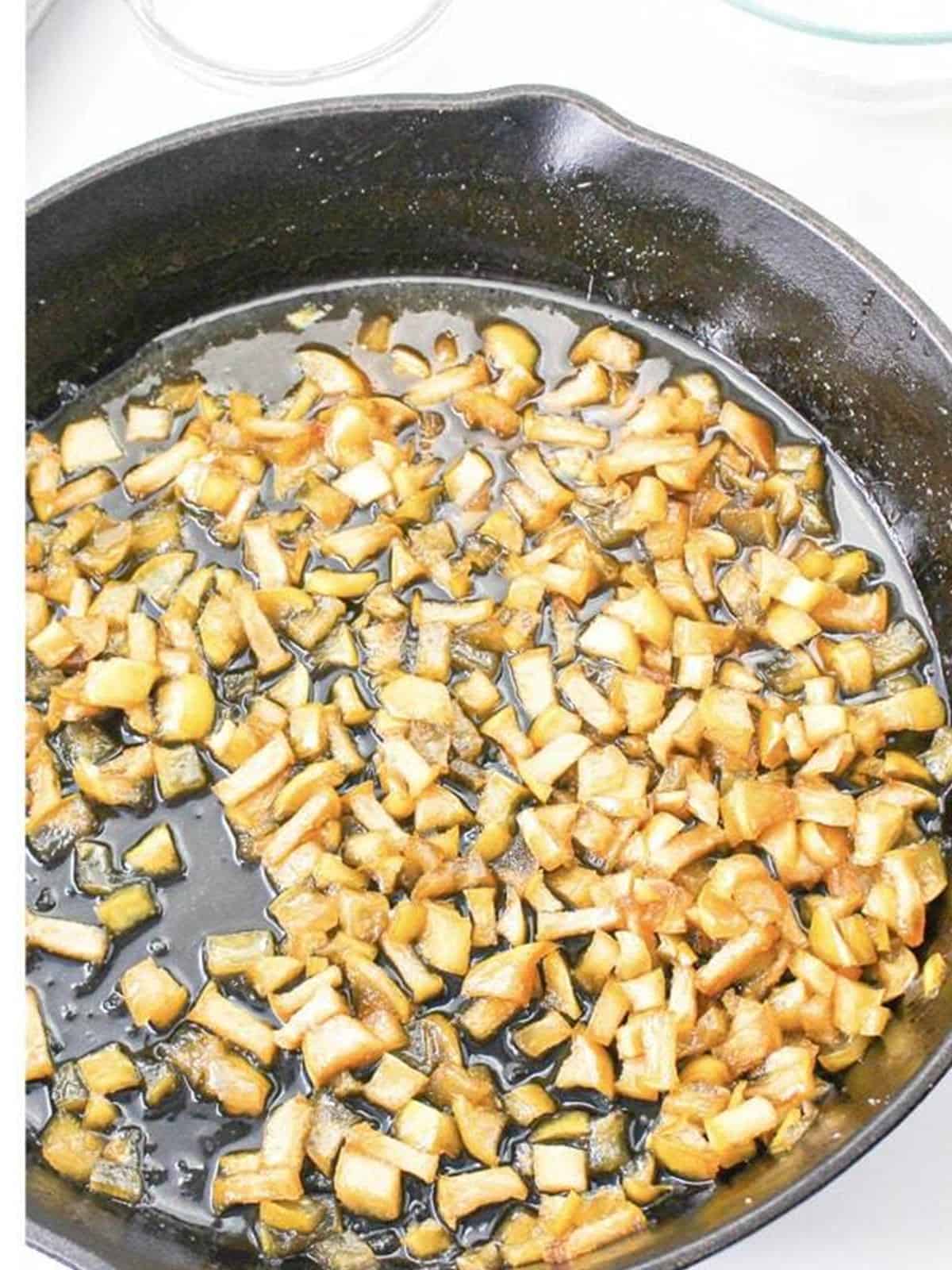 Diced apple pie filling cooking in a cast iron skillet.