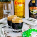 Two layered Baby Guinness shots that look like tiny pints of Guinness with a dark base and creamy top.