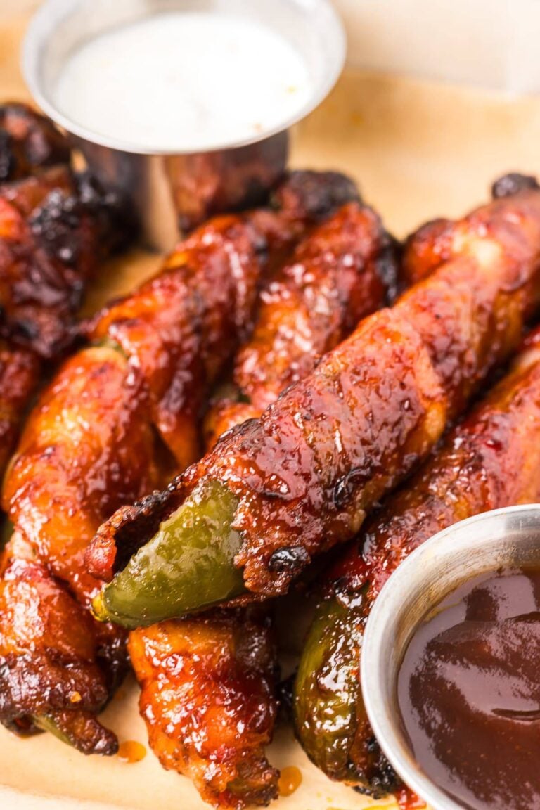 A platter of crispy air fryer Bacon Wrapped Pickles glazed with BBQ sauce and served with ranch dressing.
