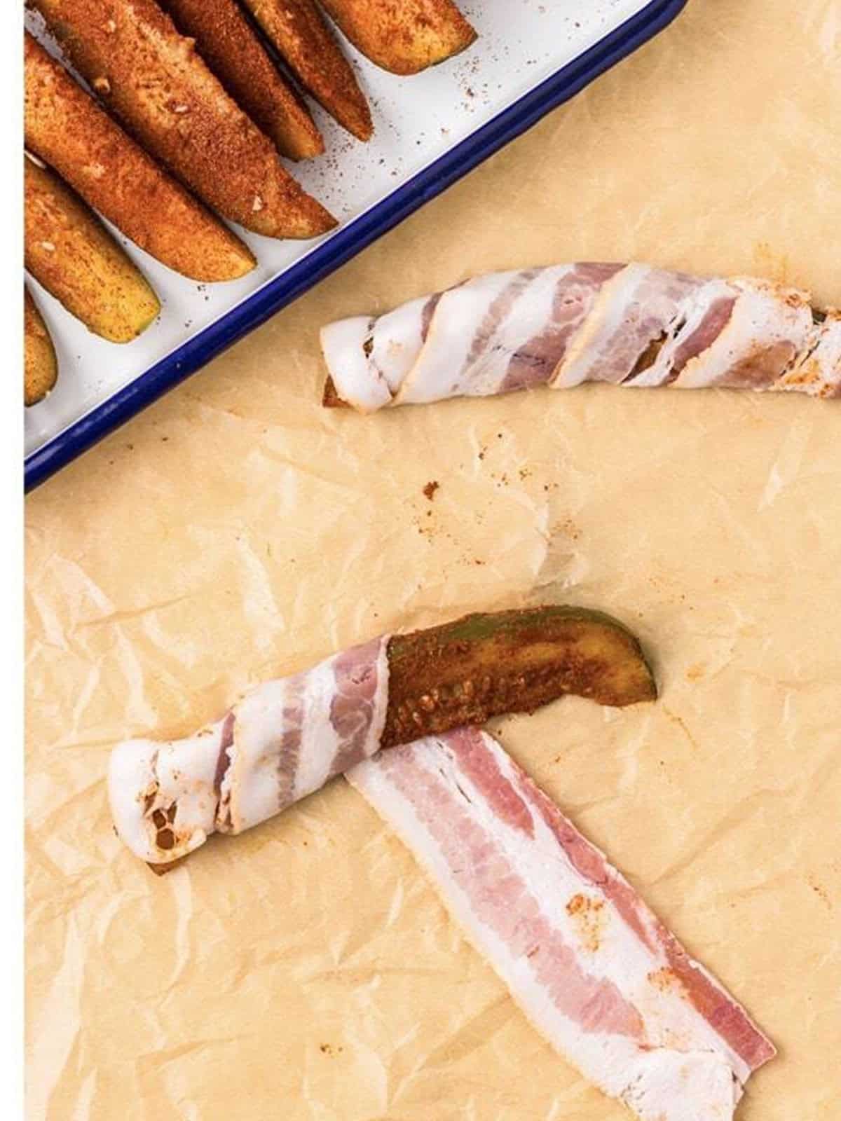 Wrapping a strip of bacon around a seasoned dill pickle spear.