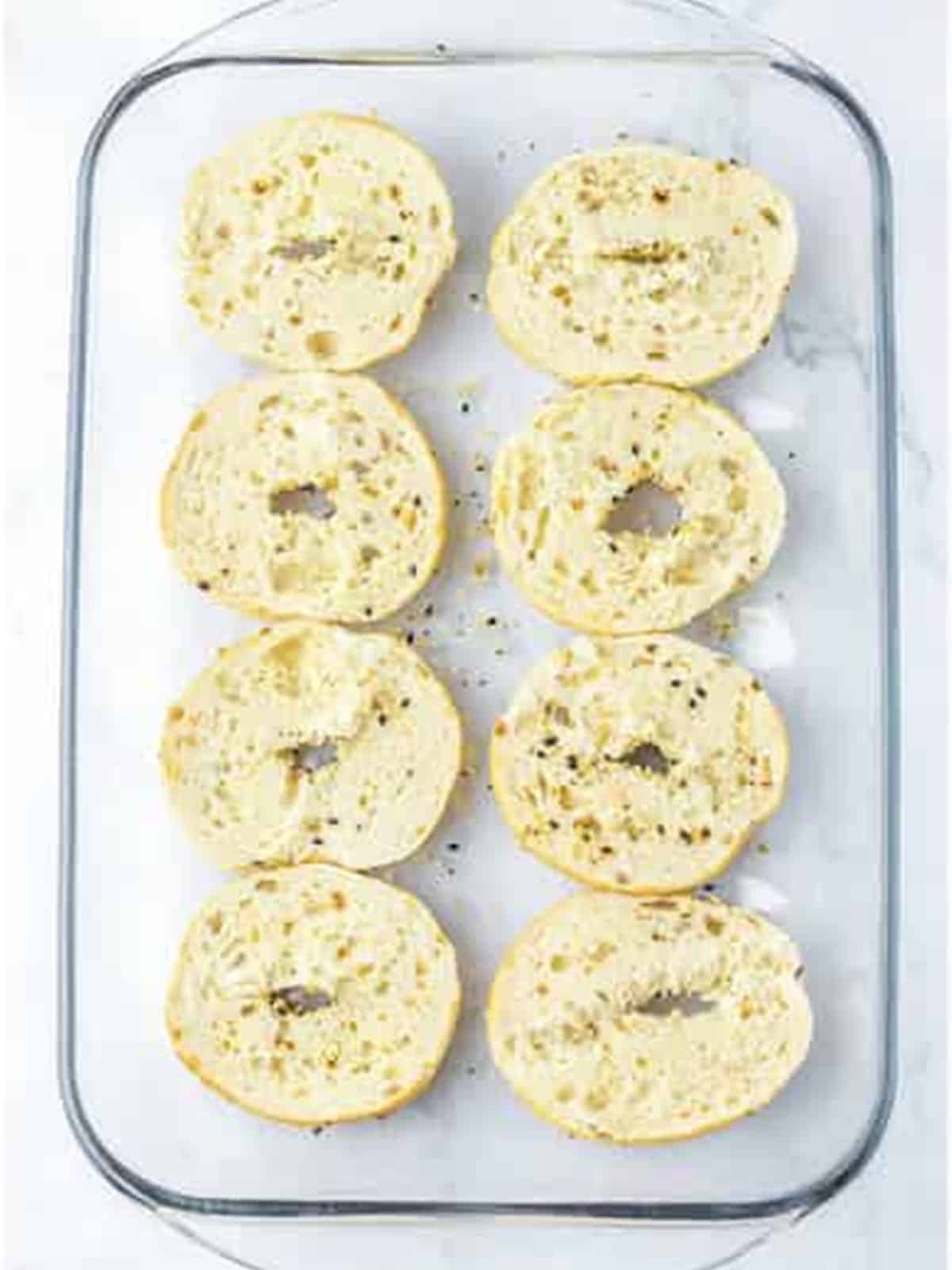Everything bagel bottoms arranged in a baking dish for breakfast sliders.