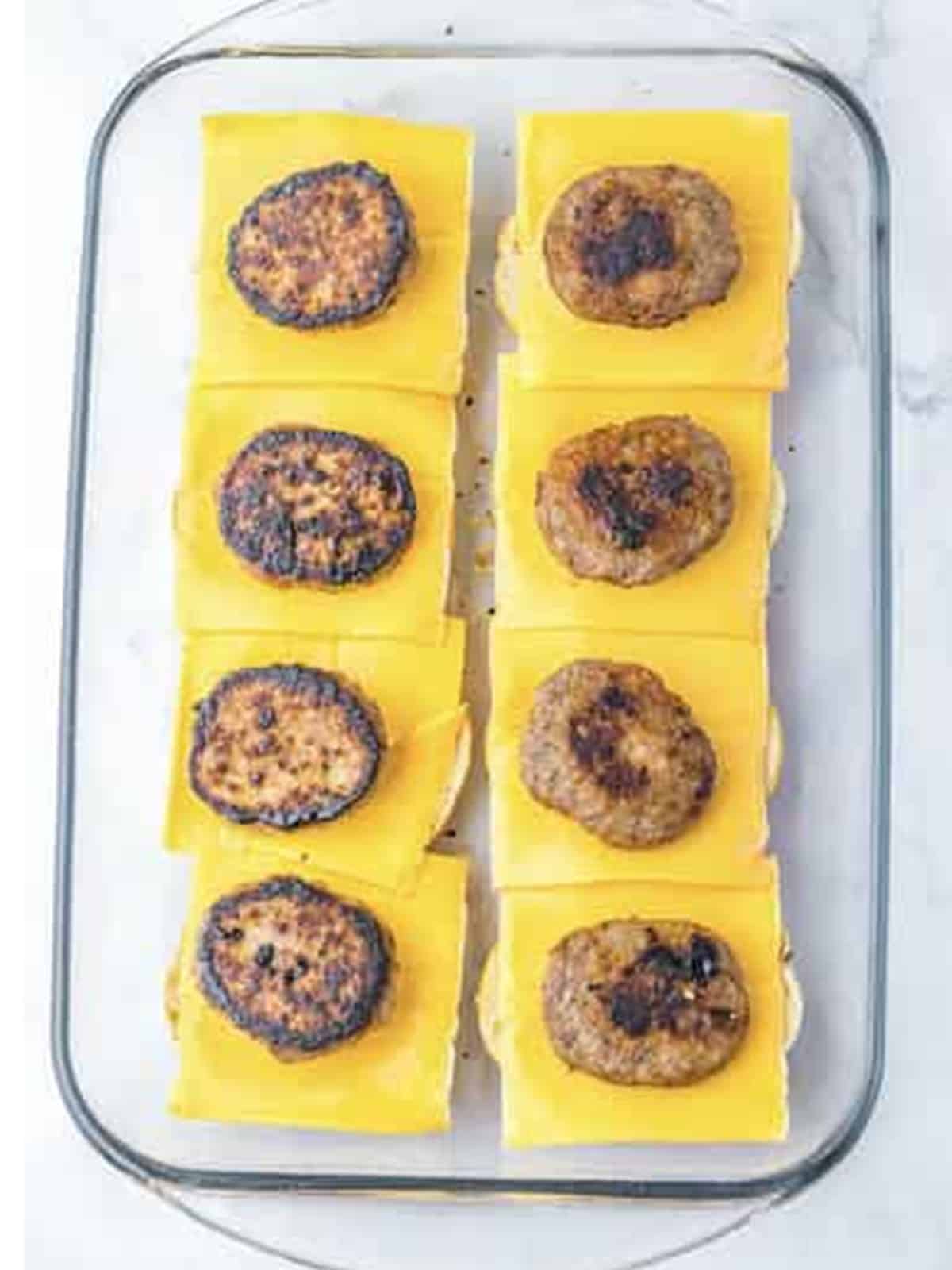 Cheddar cheese and cooked sausage patties layered on bagel bottoms.