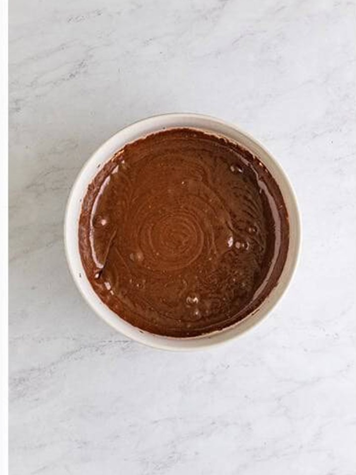 Brownie batter mixed smooth in a white bowl for baileys brownies.