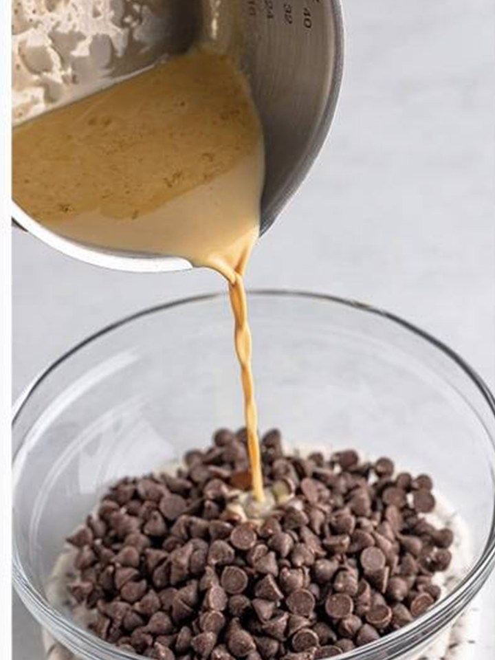 Hot Baileys and heavy cream being poured over semi sweet chocolate chips for the ganache.