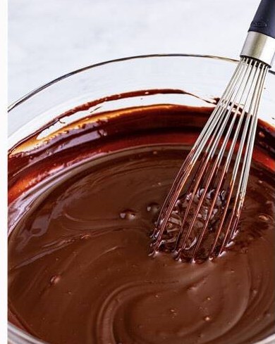 The baileys ganache whisked smooth and glossy in a glass bowl.