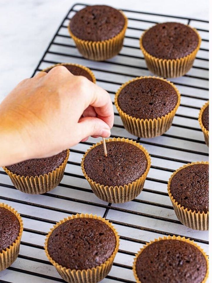 A toothpick poking holes all over a baileys cupcake for the soak.