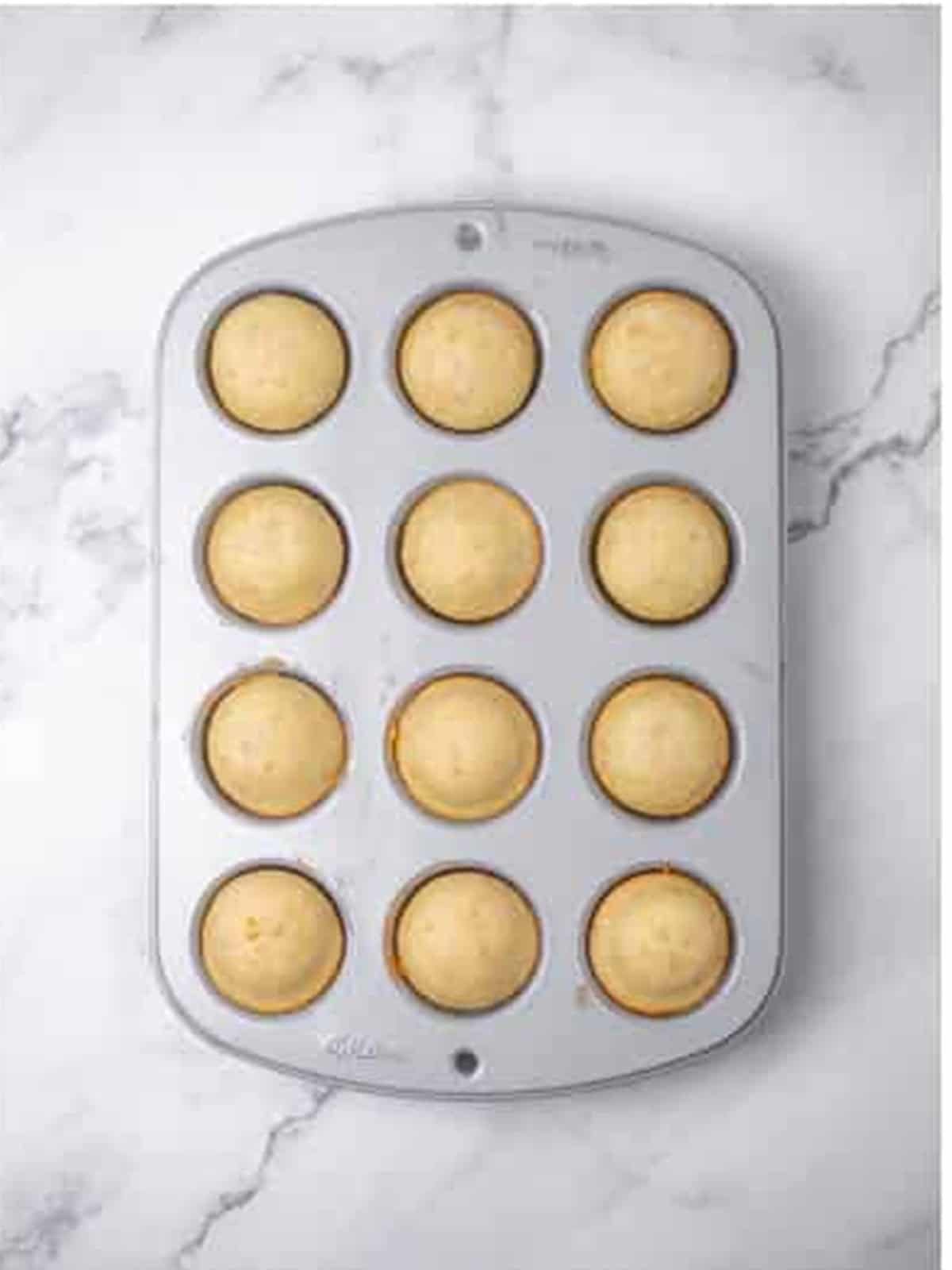 Golden baked donut holes fresh from the oven in a mini muffin tin.