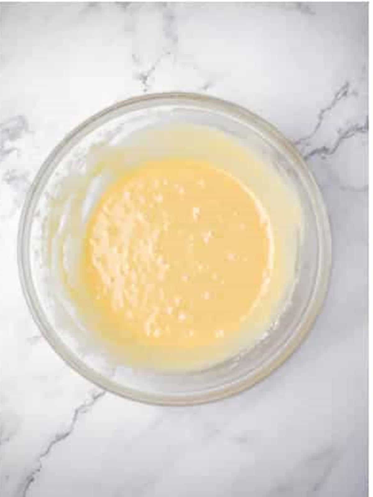 Melted butter, egg, vanilla, sugar, and milk whisked together in a glass bowl.