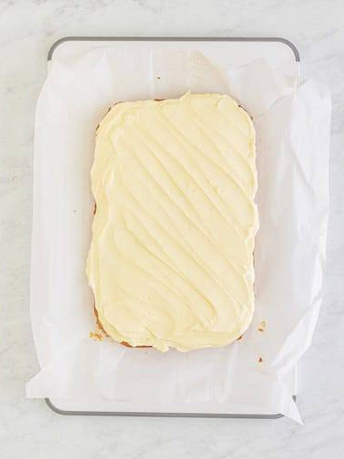 Cream cheese frosting smoothed over the cooled Banana Blondies before slicing.