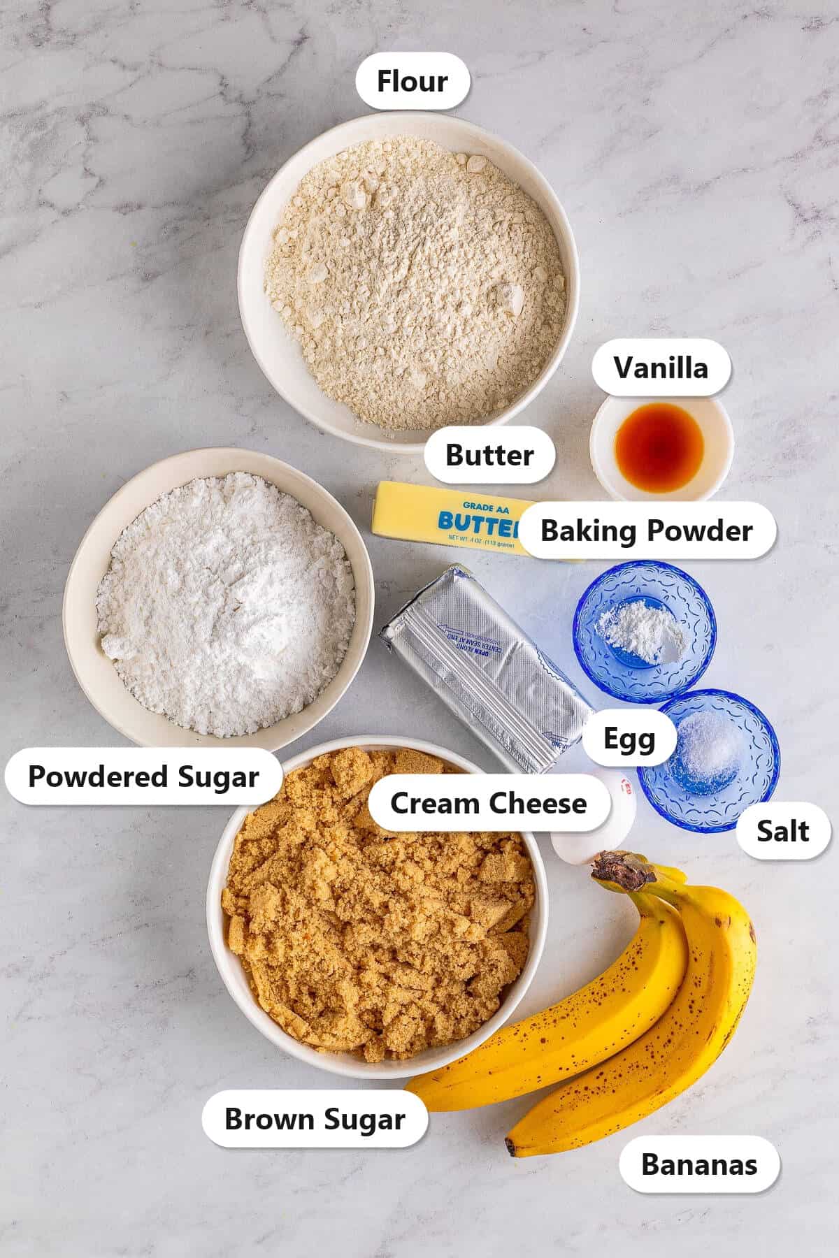 Labeled ingredients to make Banana Blondies, flour, brown sugar, bananas, butter, cream cheese, powdered sugar, egg, and vanilla.