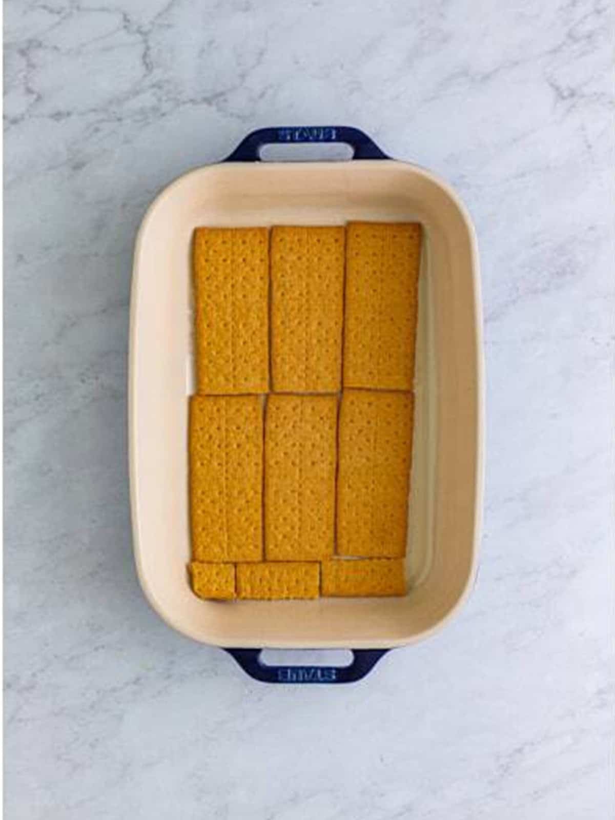 Graham crackers layered in the bottom of a baking dish for banana icebox cake.