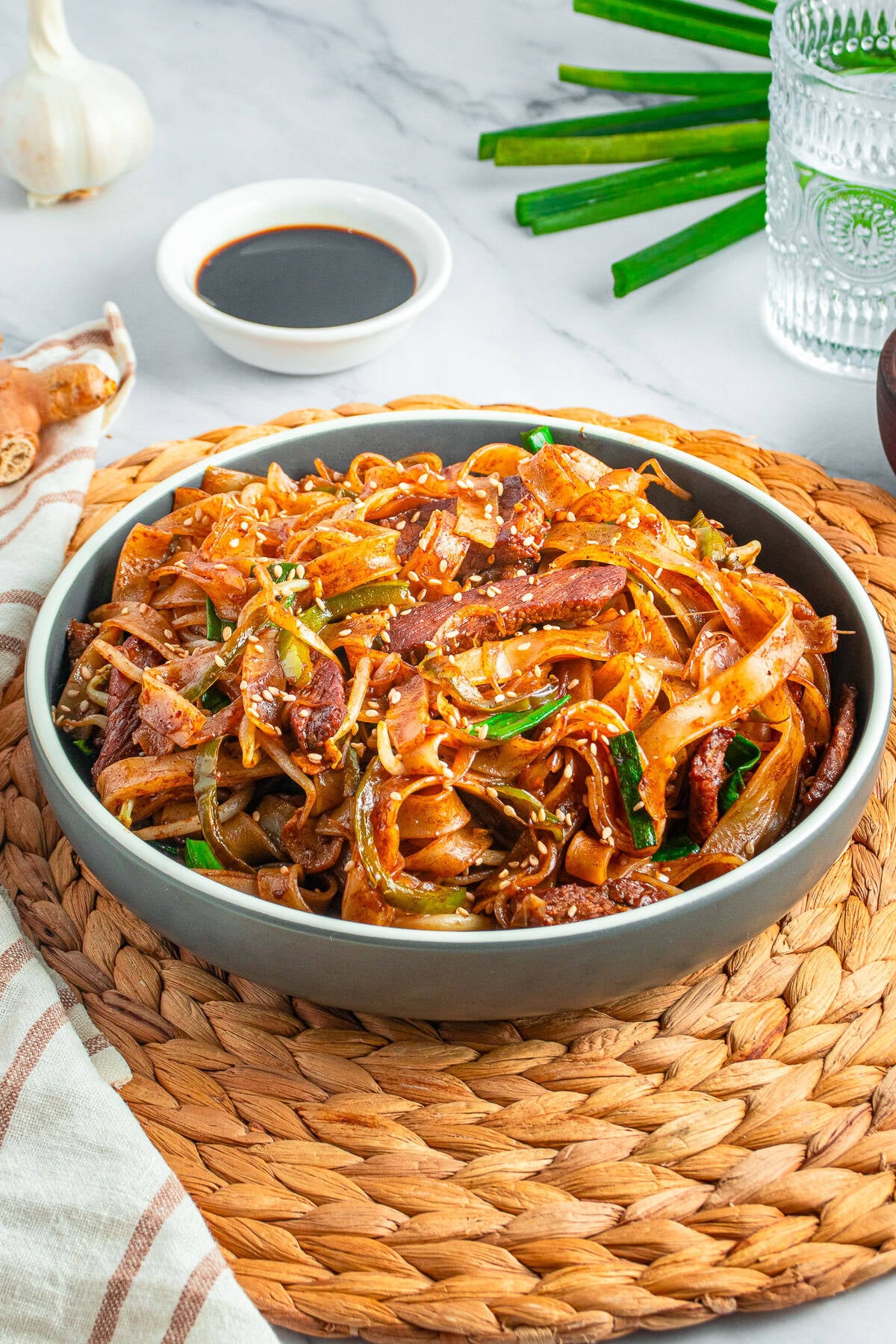 A bowl of Beef Chow Ho Fun with wide rice noodles, seared flank steak, and vegetables in a savory soy sauce.