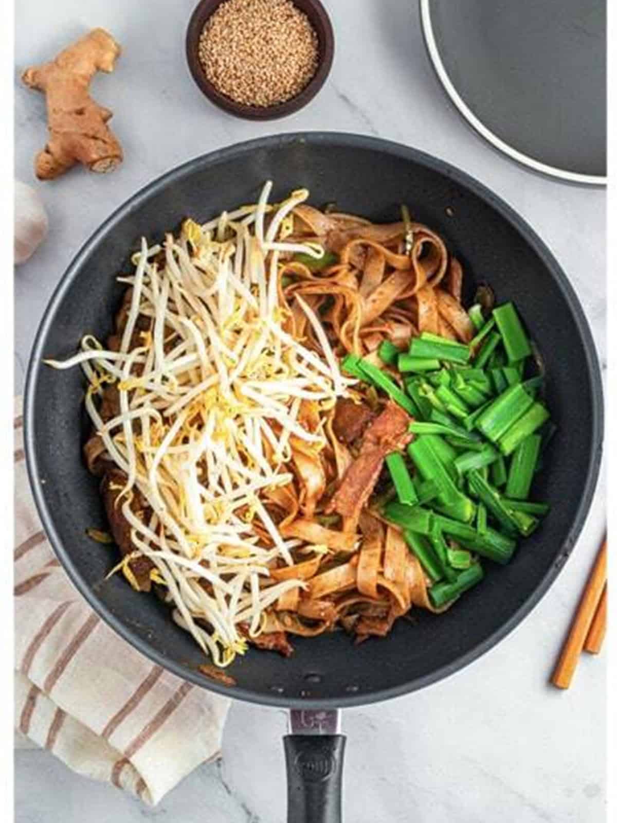 Bean sprouts and green onions added to the noodles and beef in the wok for Beef Chow Ho Fun.