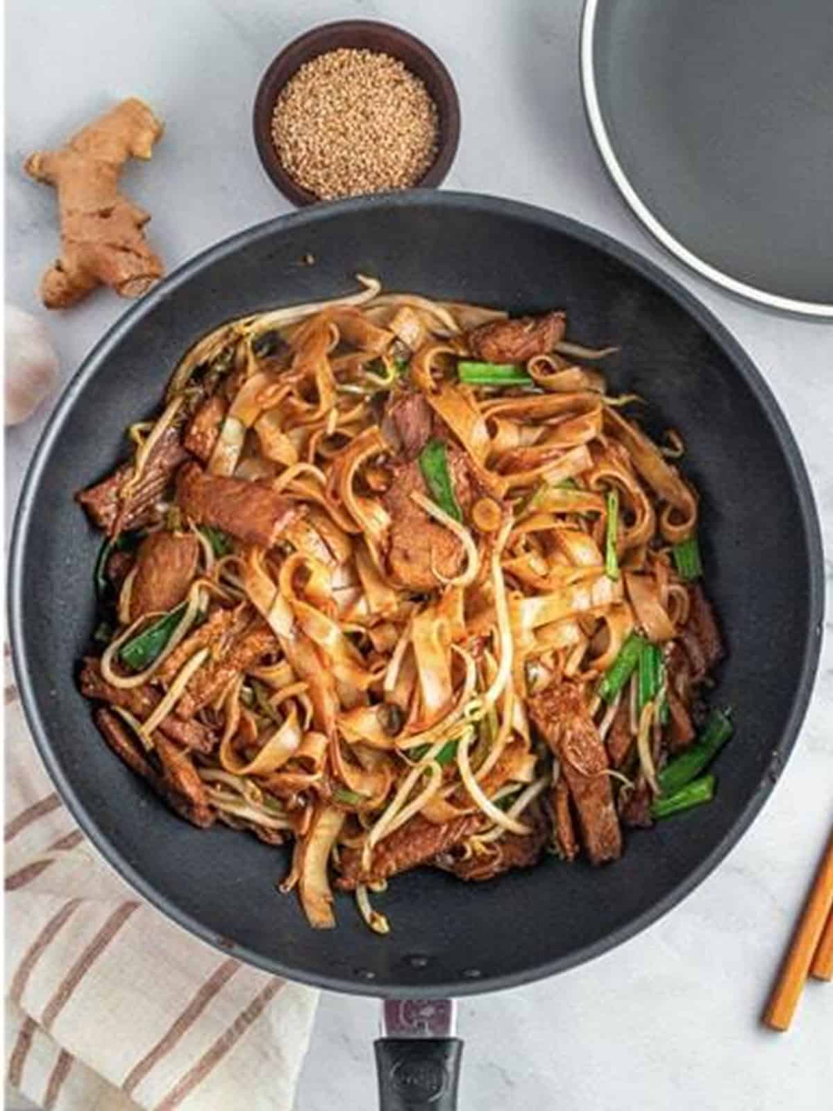 Finished Beef Chow Ho Fun tossed together in the wok and garnished with sesame seeds.