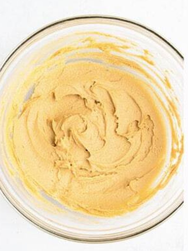 Butter, brown sugar, and cookie butter creamed together in a glass mixing bowl.