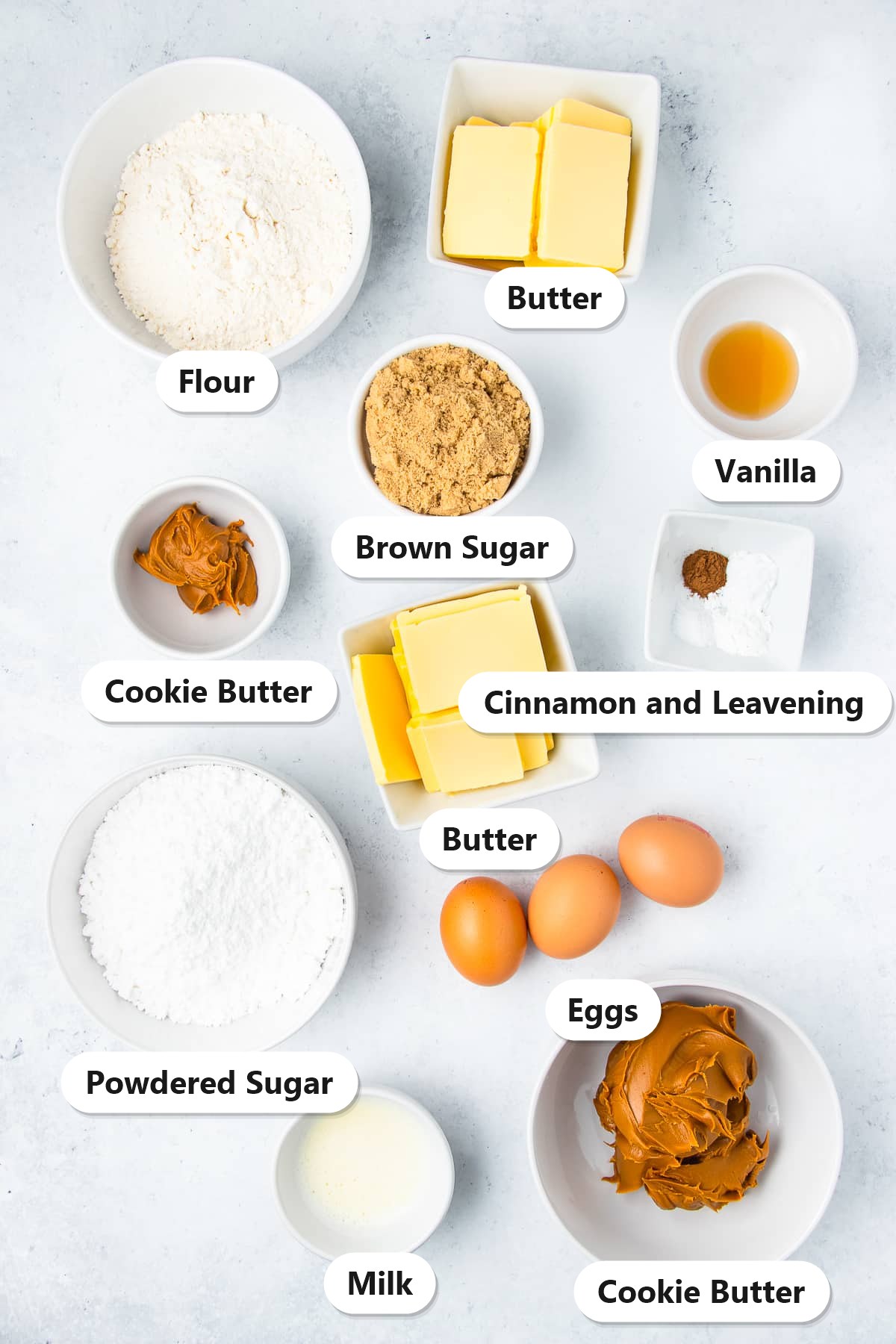 Ingredients to make Biscoff cupcakes: flour, butter, brown sugar, cookie butter, eggs, vanilla, cinnamon, leavening, powdered sugar, and milk.