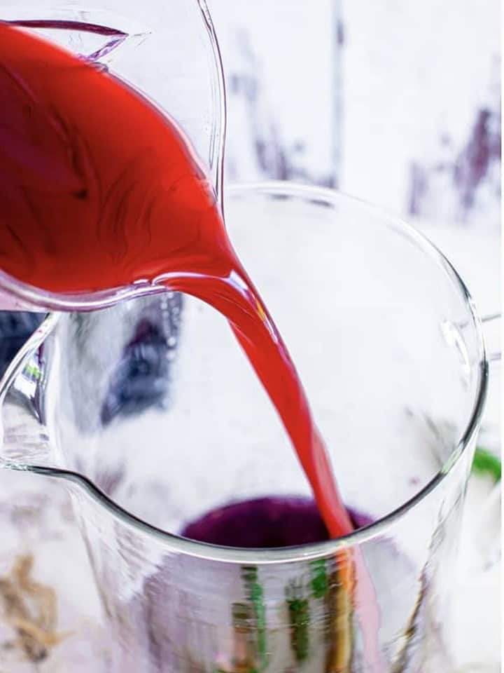 Pomegranate blueberry juice poured into the pitcher with the muddled blackberries.