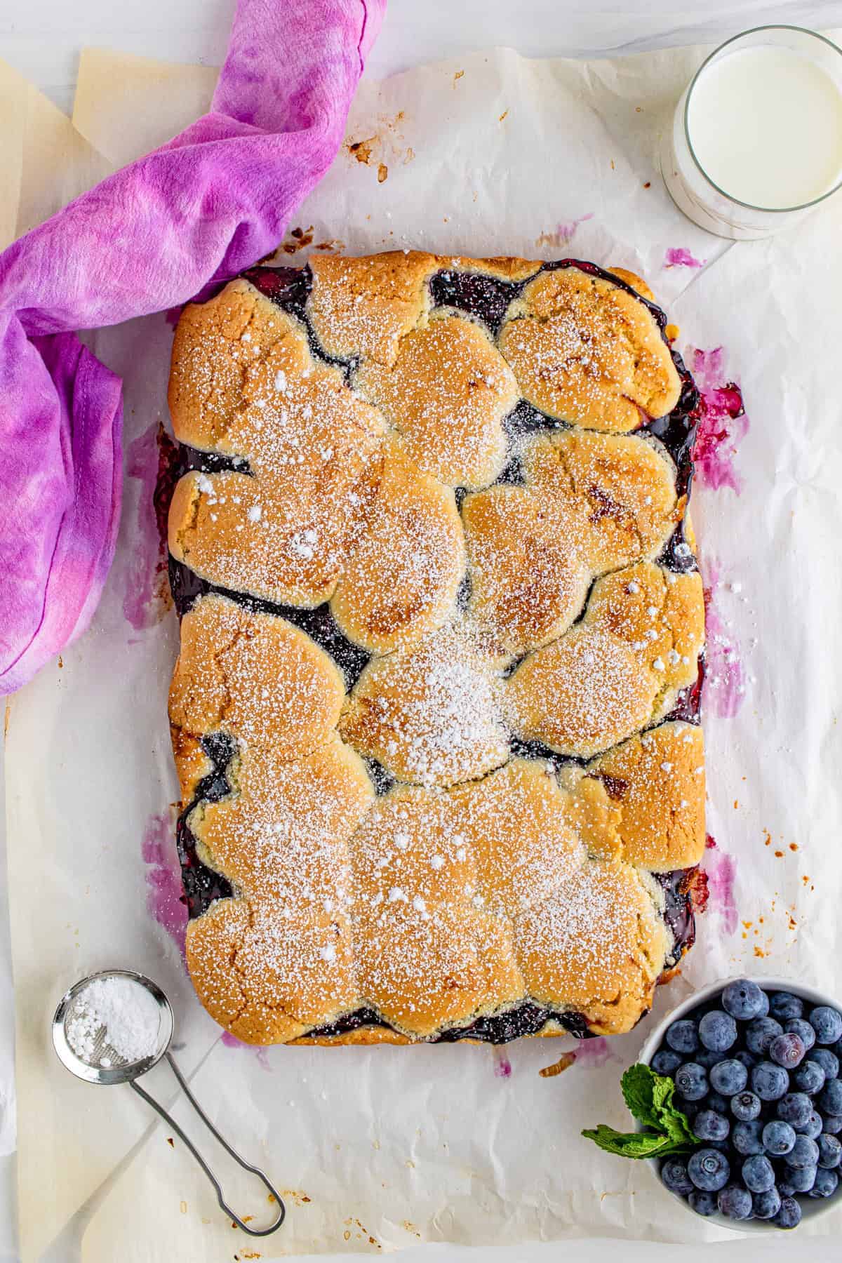 A whole pan of golden blueberry bars dusted with powdered sugar and cut into squares.