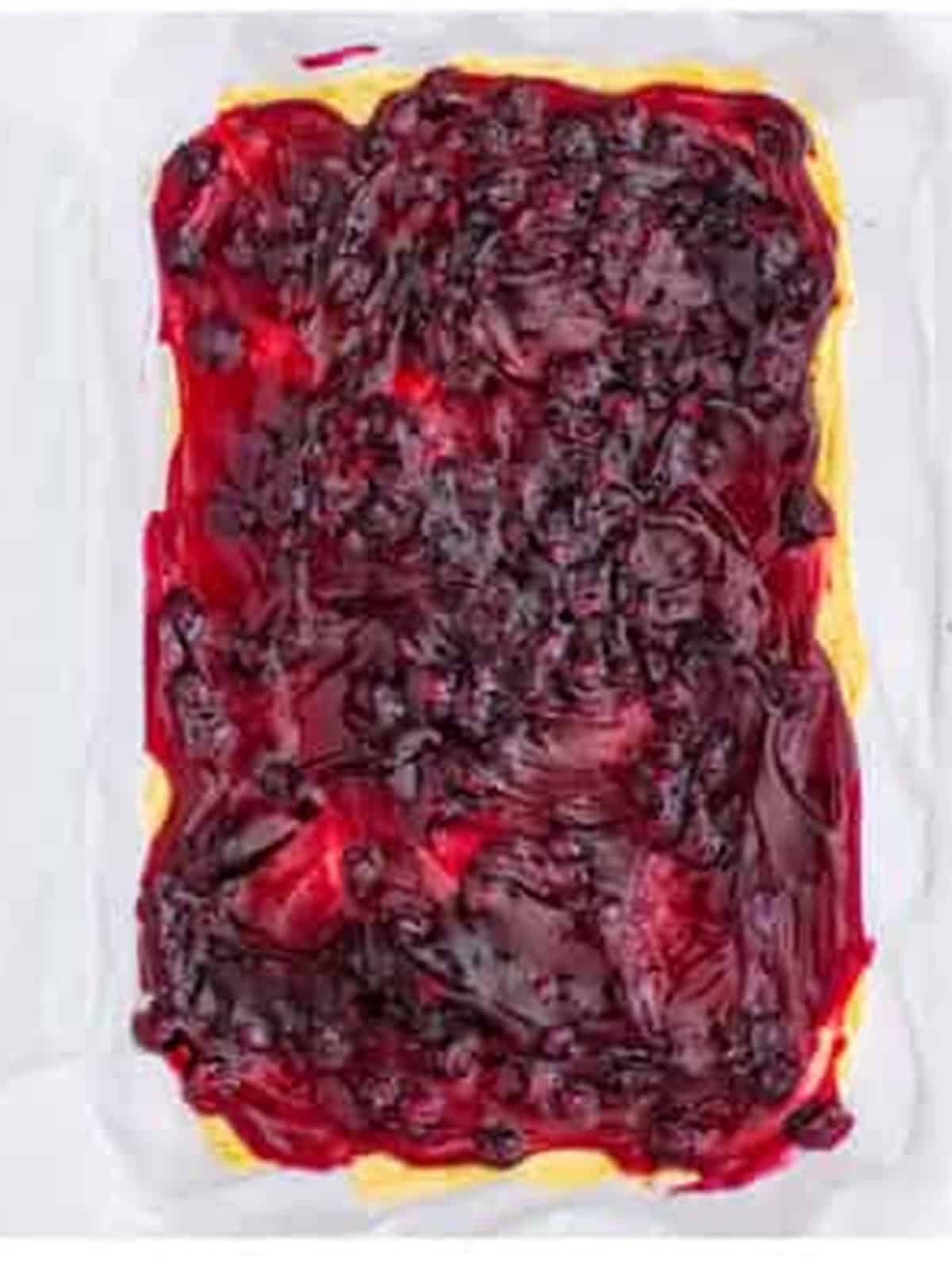 Blueberry pie filling spread over the pressed dough layer for blueberry bars.
