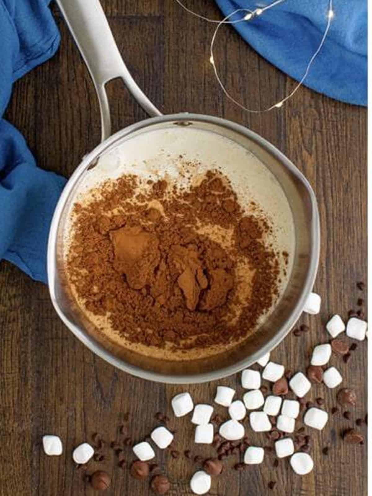 Milk, heavy cream, cocoa powder, and sugar in a saucepot for boozy hot chocolate.
