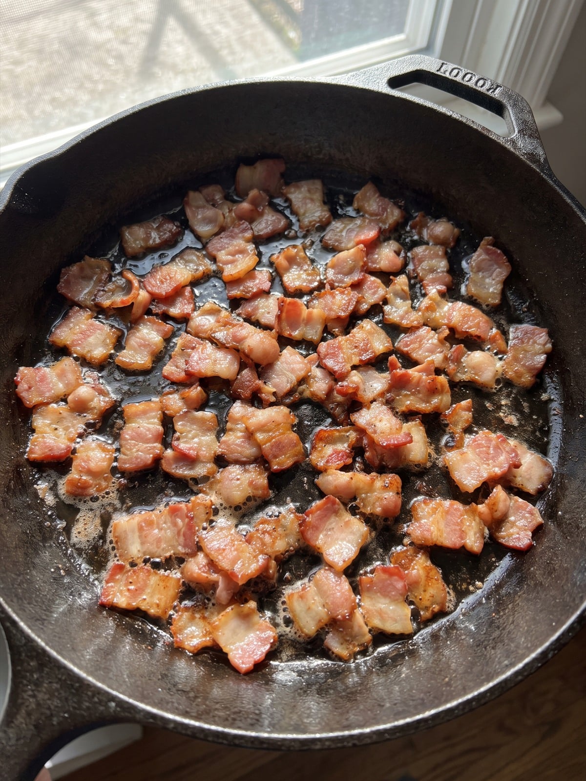 Chopped bacon crisping in a skillet.