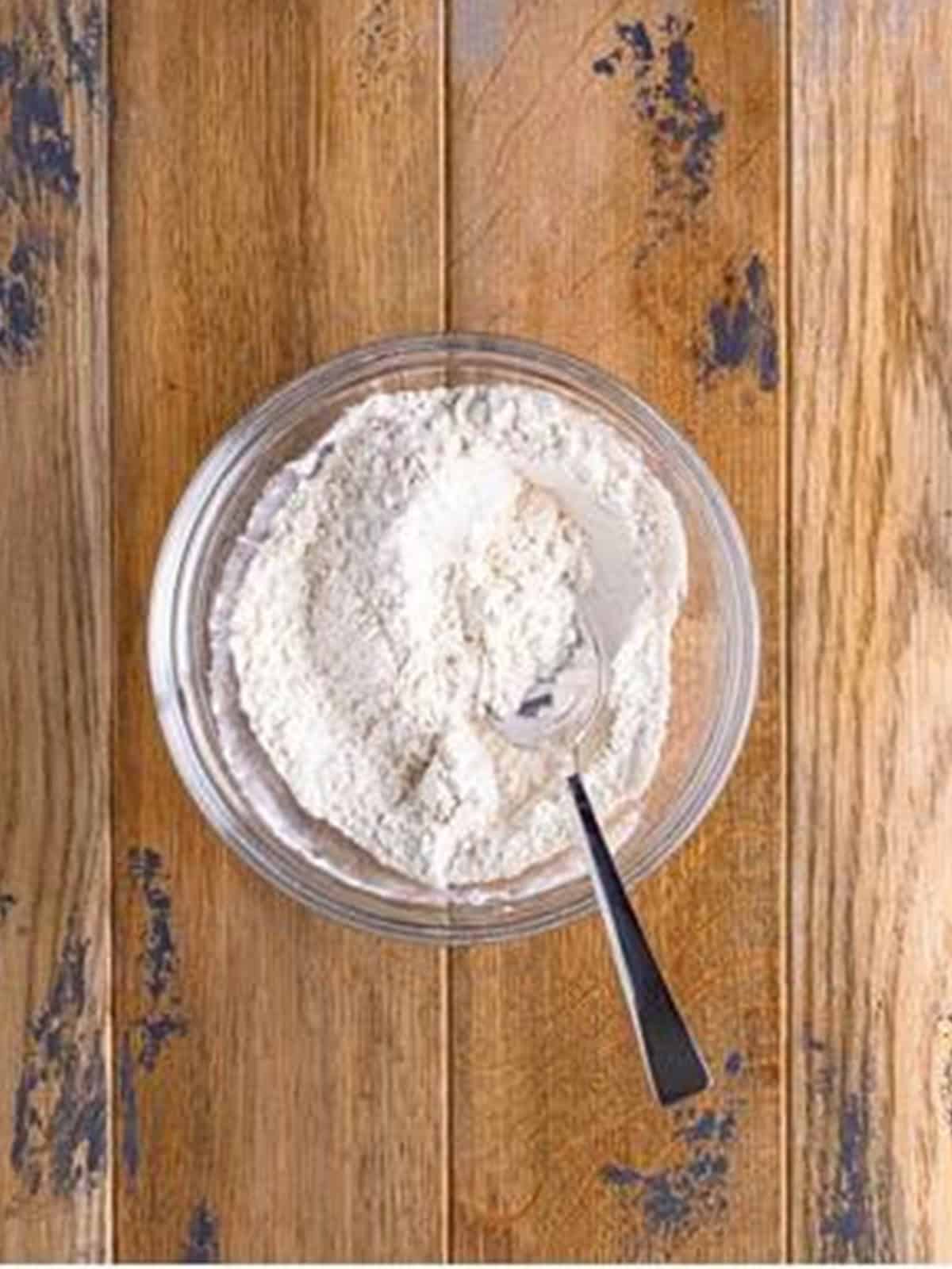 Flour, baking soda, baking powder, and salt stirred together in a bowl.