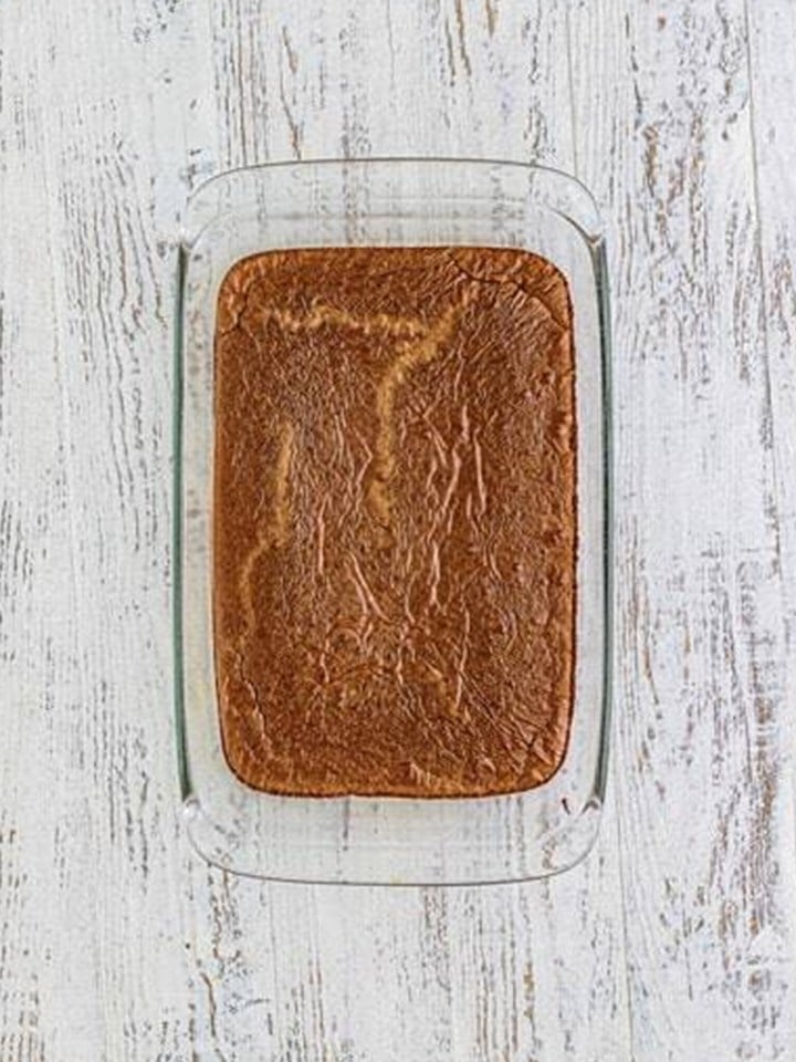 Baked brownie slab cooling in a glass baking dish for brownie truffles.