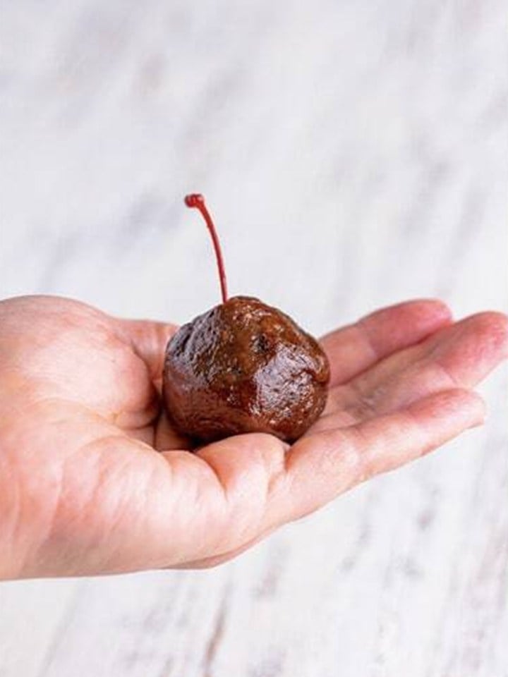 A smooth brownie truffle ball rolled around the hidden cherry in a hand.