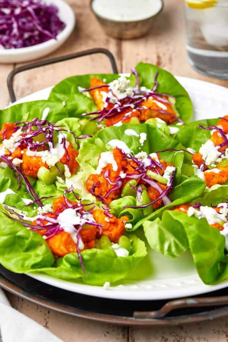 A plate of buffalo chicken lettuce wraps filled with crispy buffalo chicken, red cabbage, celery, and blue cheese.