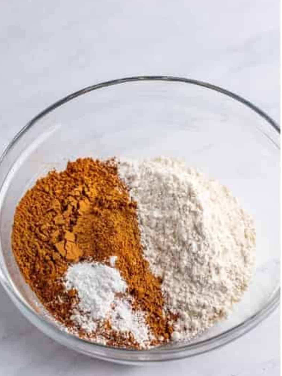 Cocoa powder, flour, and baking powder in a glass bowl for Butterfinger brownies.