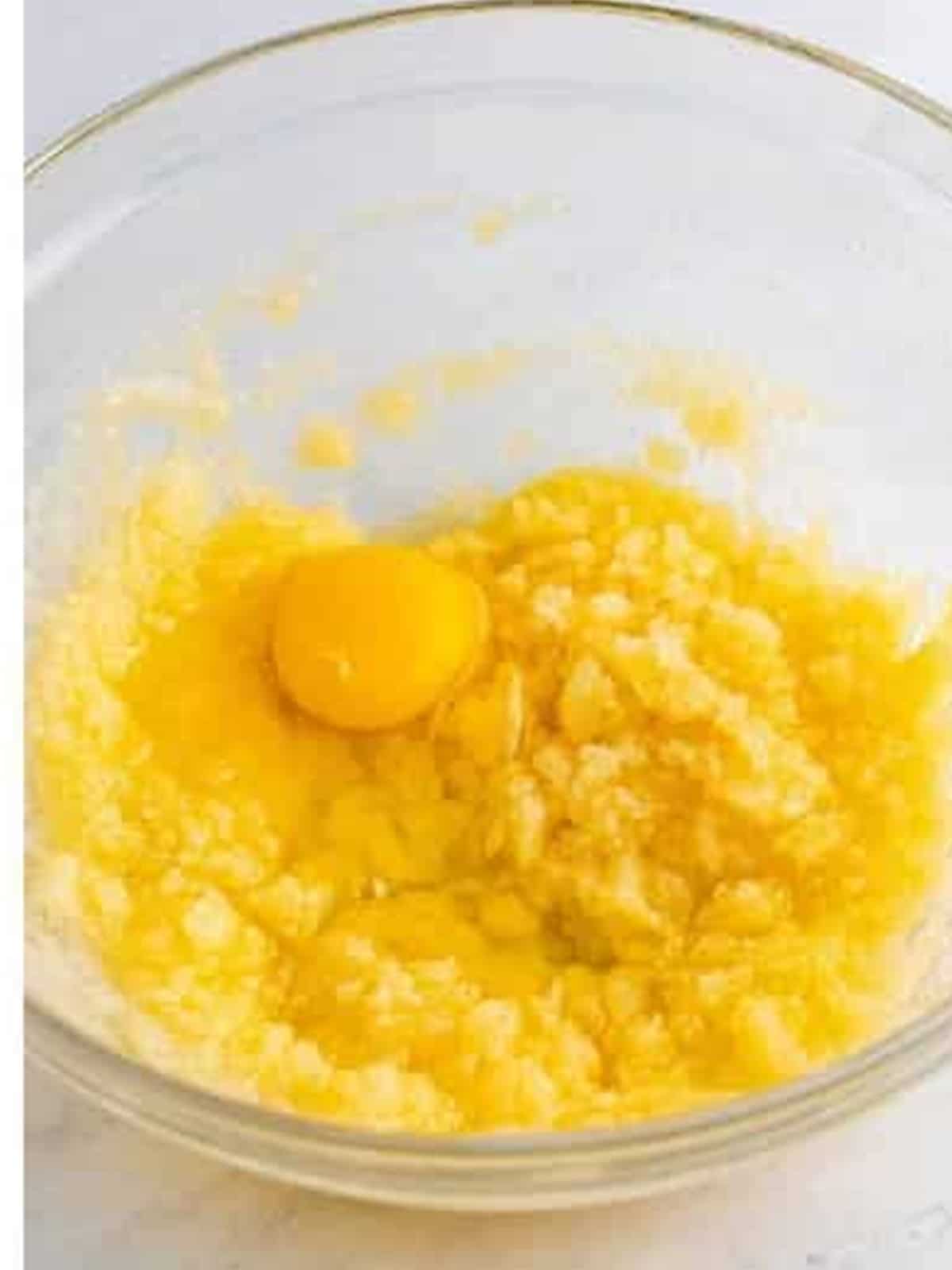 Creamed butter, sugar, and oil with an egg being added for Butterfinger brownie batter.