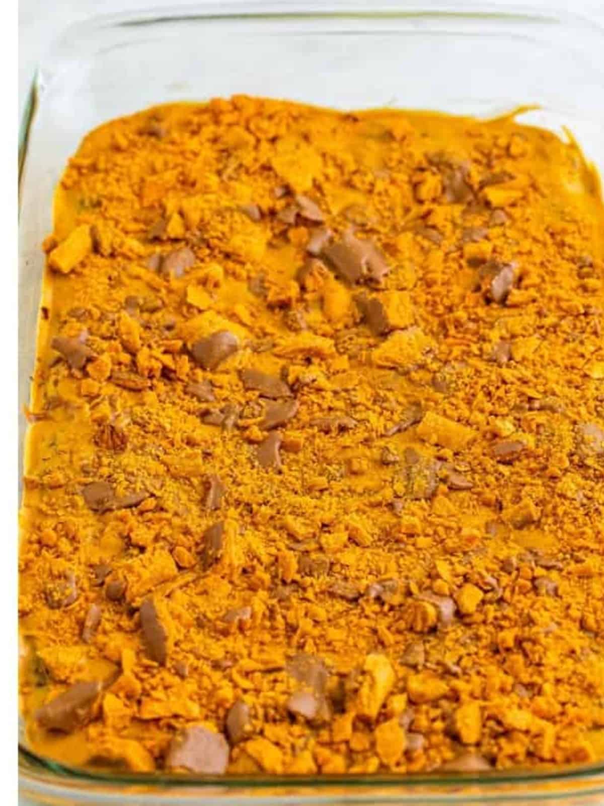 Crushed Butterfinger candy bars sprinkled over peanut butter topped brownies.