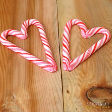 Two finished candy cane hearts on a wooden table made from molded peppermint candy canes.