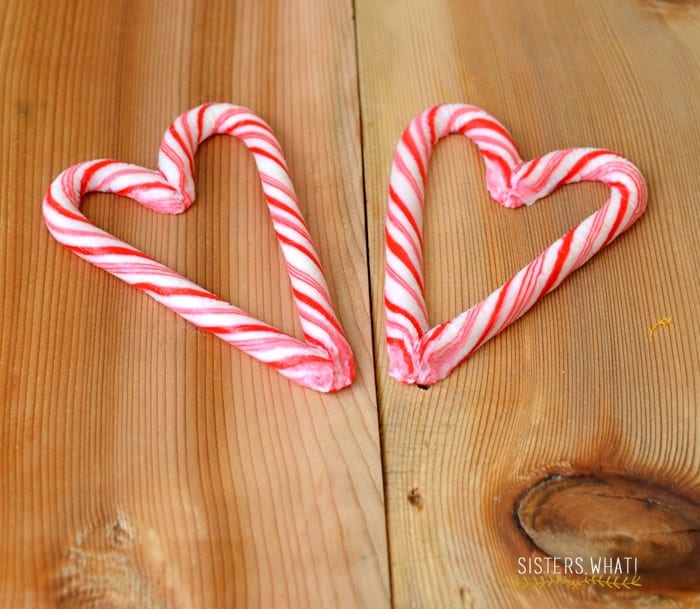 Two finished candy cane hearts on a wooden table made from molded peppermint candy canes.