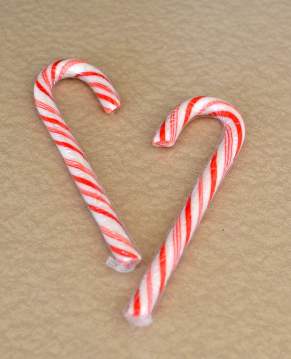 Two unwrapped candy canes arranged in a heart shape, the only ingredient needed for candy cane hearts.