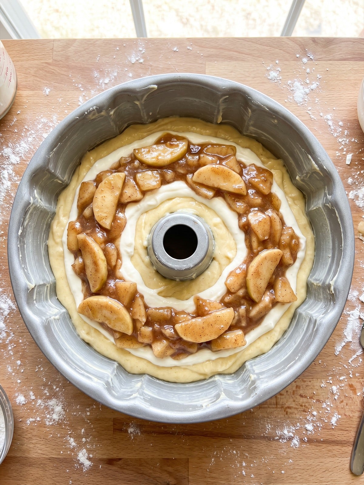 Cake batter, cheesecake filling, and apple pie filling layered in a bundt pan.