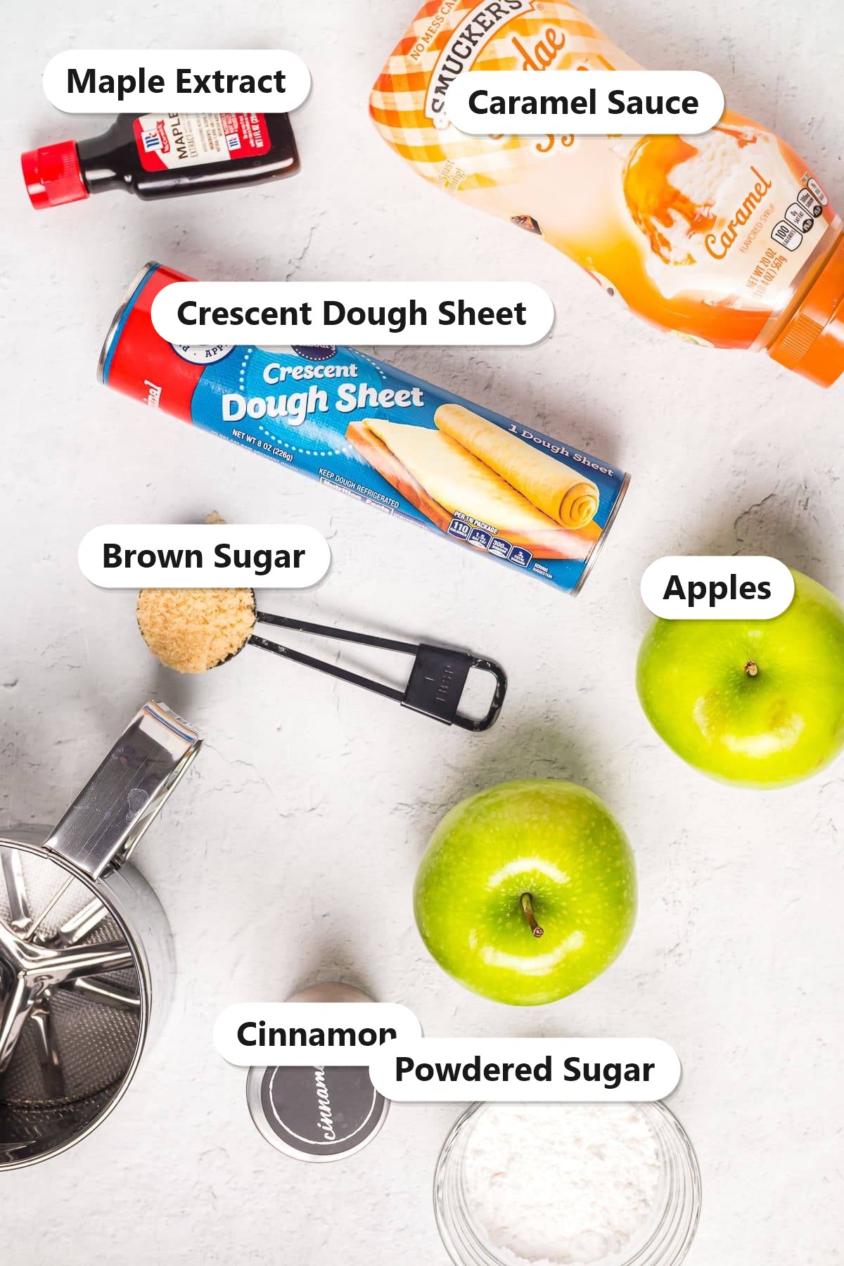 Labeled ingredients for caramel apple donut holes including crescent dough sheet, apples, caramel sauce, brown sugar, cinnamon, maple extract, and powdered sugar.