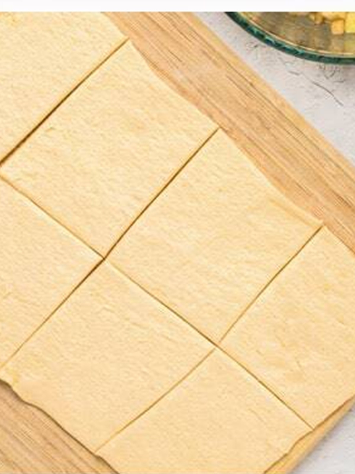 Crescent dough sheet cut into squares on a floured surface.