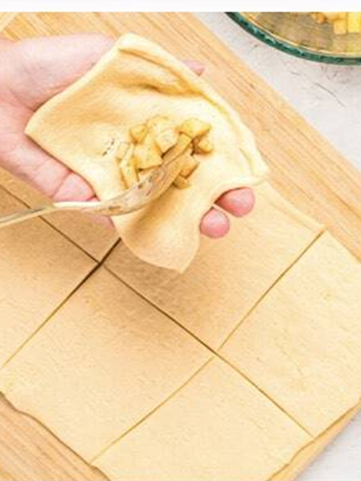 A spoonful of caramel apple filling placed in the center of a dough square and sealed.