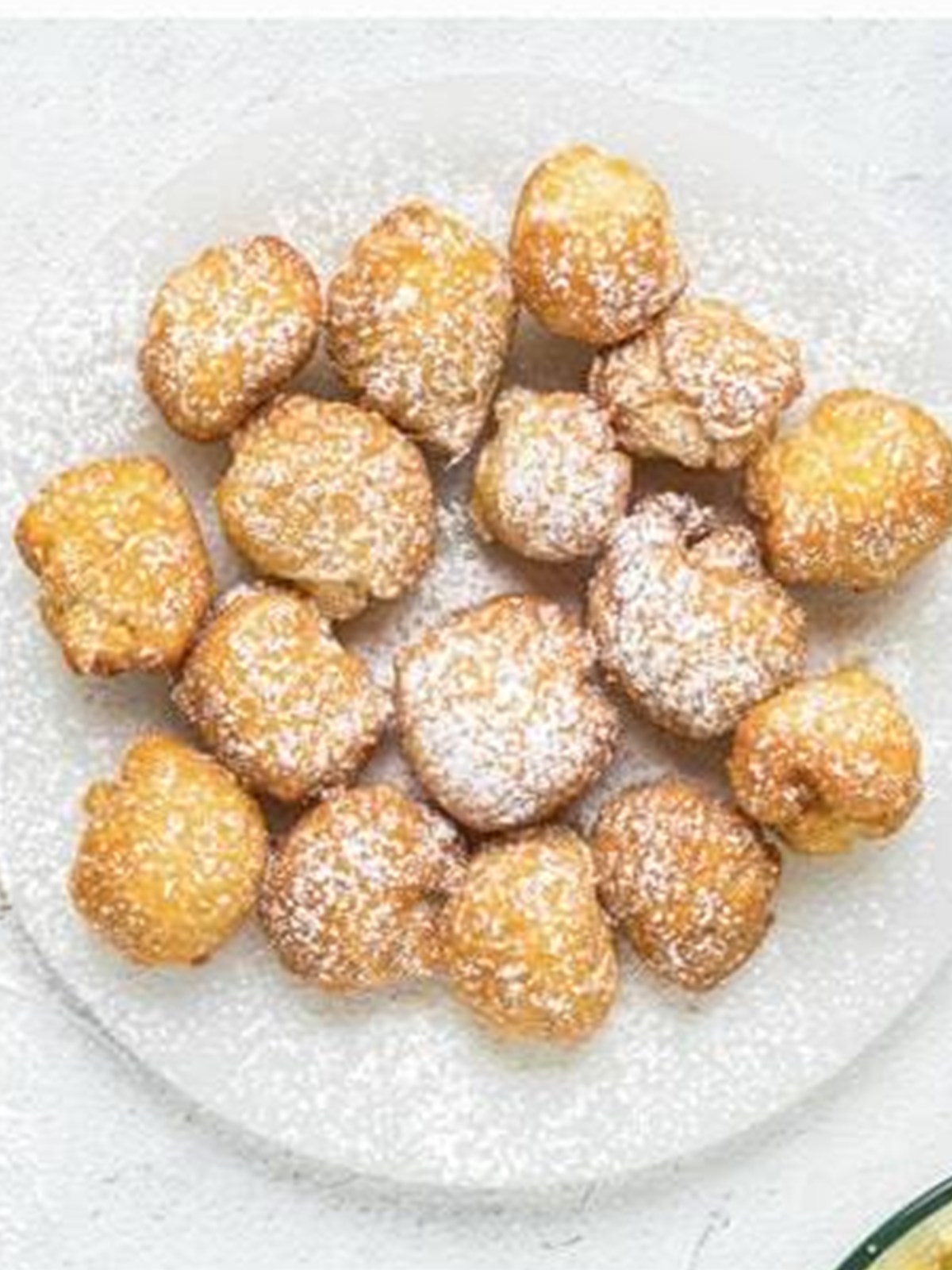 Caramel apple stuffed donut holes dusted with powdered sugar on a plate.