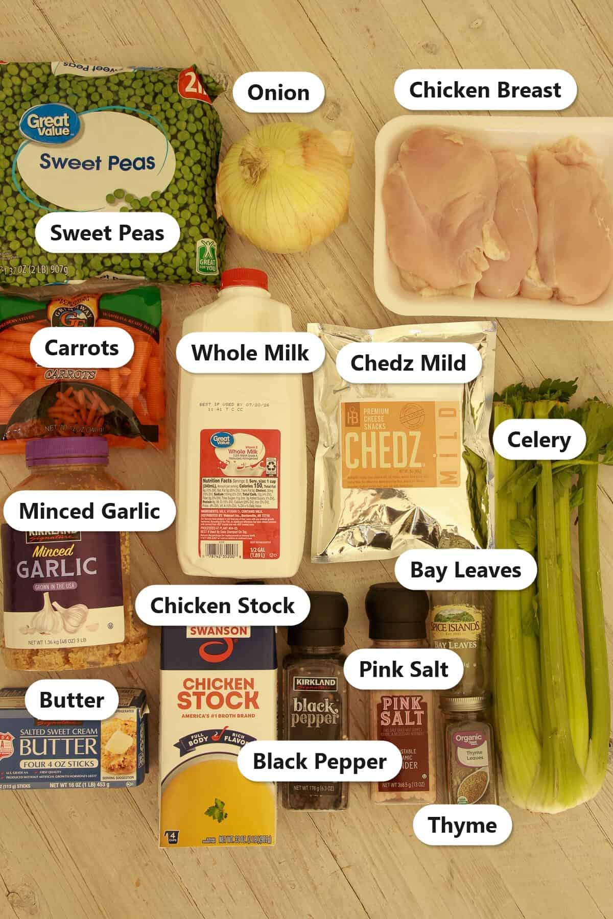 Labeled ingredients to make Chedz cheesy chicken pot pie including sweet peas, onion, chicken breast, carrots, whole milk, Chedz Mild cheese snacks, celery, minced garlic, butter, chicken stock, black pepper, pink salt, bay leaves, and thyme.