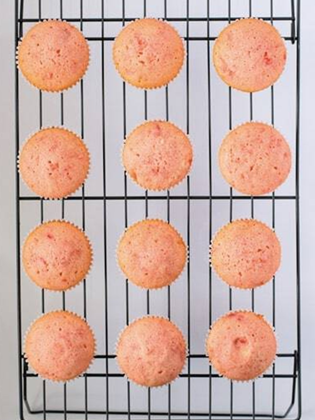 Baked cherry cupcakes cooling on a wire rack.