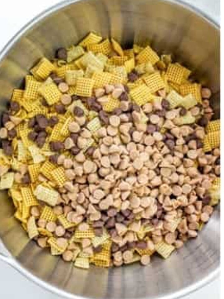 Chex cereal stirred with peanut butter chips and chocolate chips in a large bowl for chex bars.