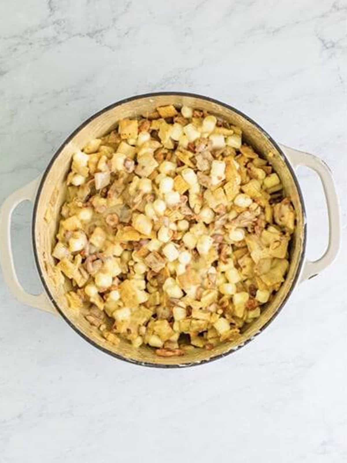 Adding chopped pretzels and honey roasted nuts to the Chex marshmallow mixture.