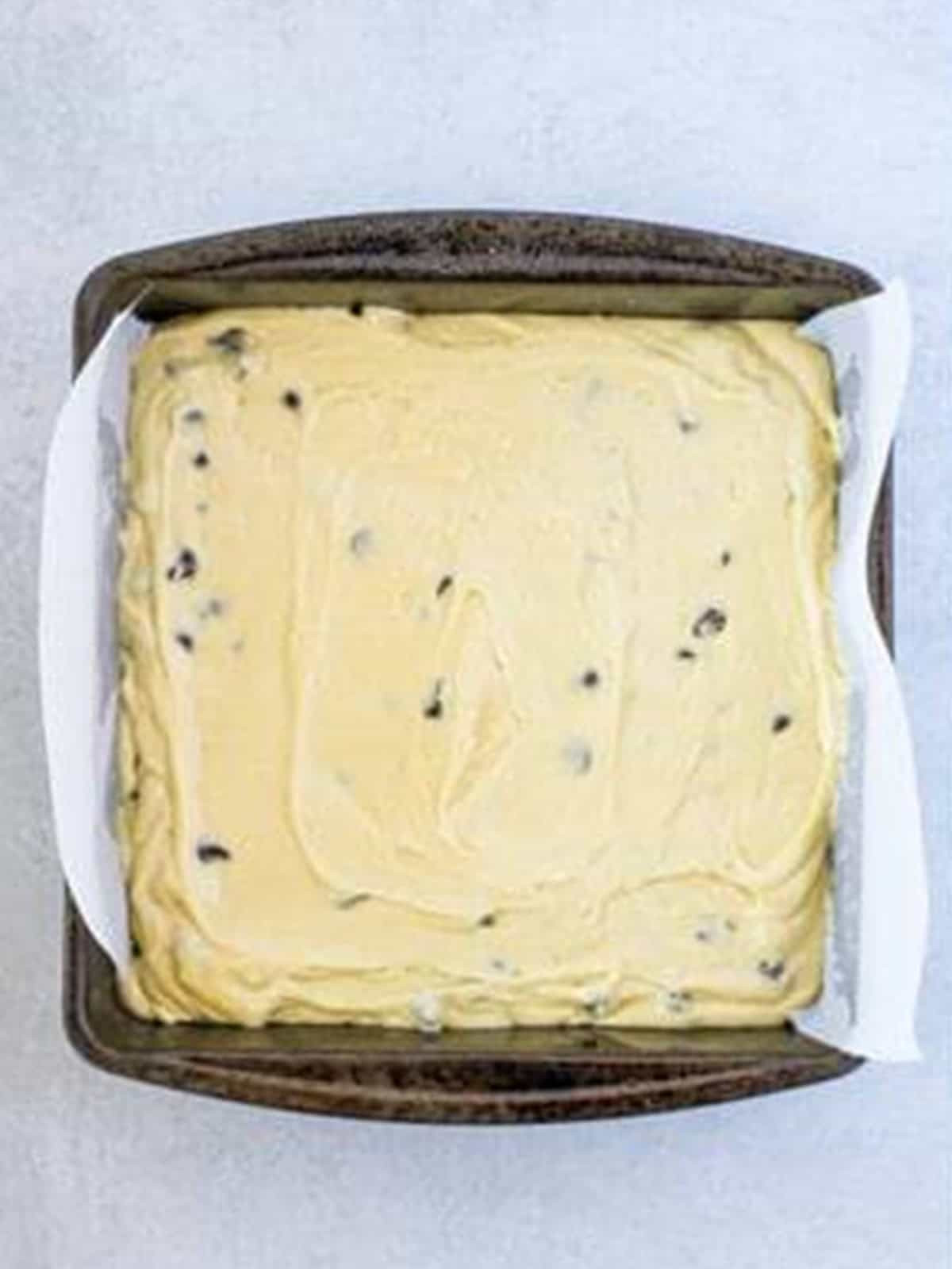 Chocolate Chip Coffee Cake batter smoothed into a parchment lined square baking pan.